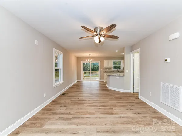 a view of an empty room with window and wooden floor