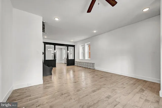 a view of an empty room with a window and wooden floor