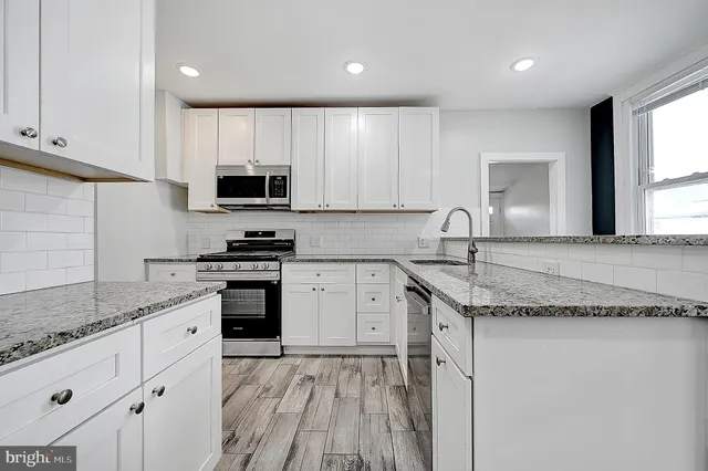 a kitchen with granite countertop a sink stainless steel appliances and white cabinets