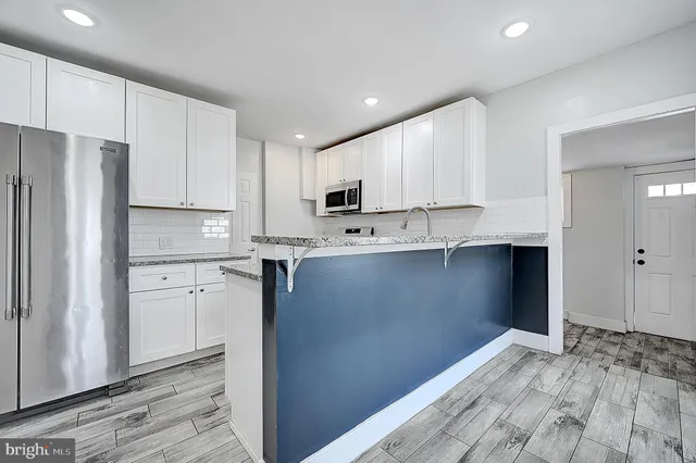 a kitchen with granite countertop white cabinets and refrigerator