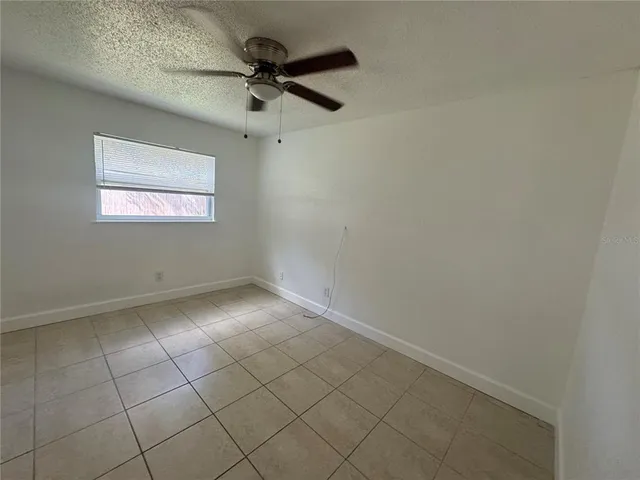an empty room with a ceiling fan and window