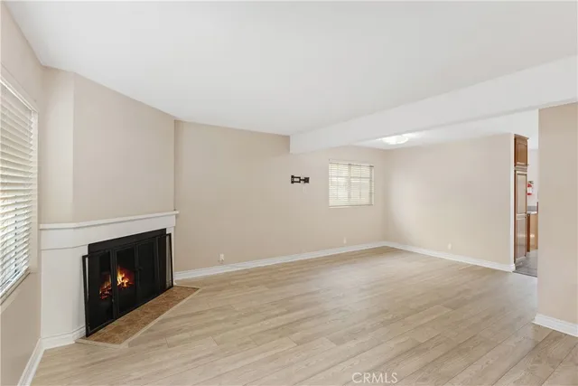 a view of an empty room with wooden floor fireplace and a window