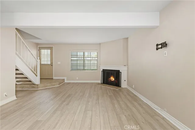 an empty room with wooden floor fireplace and windows