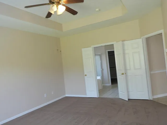 an empty room with closet and a chandelier fan