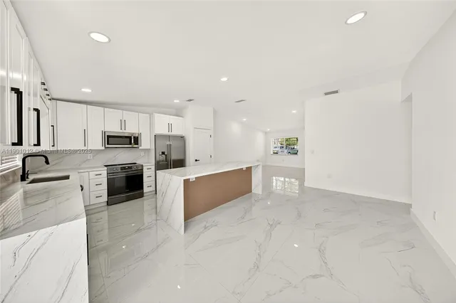 a large kitchen with a large counter top stainless steel appliances and cabinets