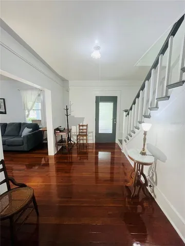a view of a livingroom with furniture wooden floor windows and a kitchen