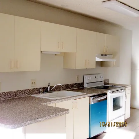 a kitchen with granite countertop a sink a stove and white cabinets