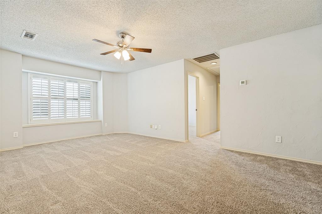 1215 Spring Creek Drive Allen, TX 75002 - Photo 14 of 40 Spacious interior room featuring plush carpet flooring, a window with white plantation shutters, a ceiling fan with integrated lighting, and neutral wall tones