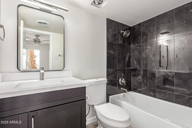 a bathroom with a bathtub shower sink vanity mirror and toilet
