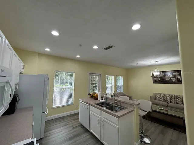 a kitchen with stainless steel appliances a sink a stove a refrigerator cabinets and living room view