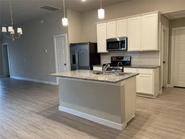 a kitchen with stainless steel appliances granite countertop a stove a sink and a microwave