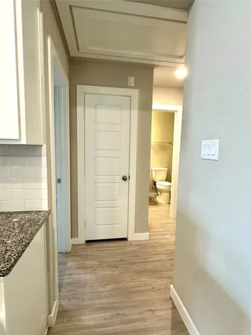 a view of a hallway with wooden floor and a bathroom