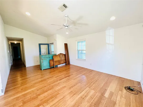 a view of an empty room with window and wooden floor