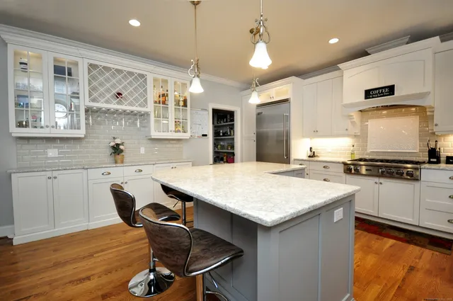 a kitchen with stainless steel appliances granite countertop a stove top oven a sink a dining table and chairs with wooden floor