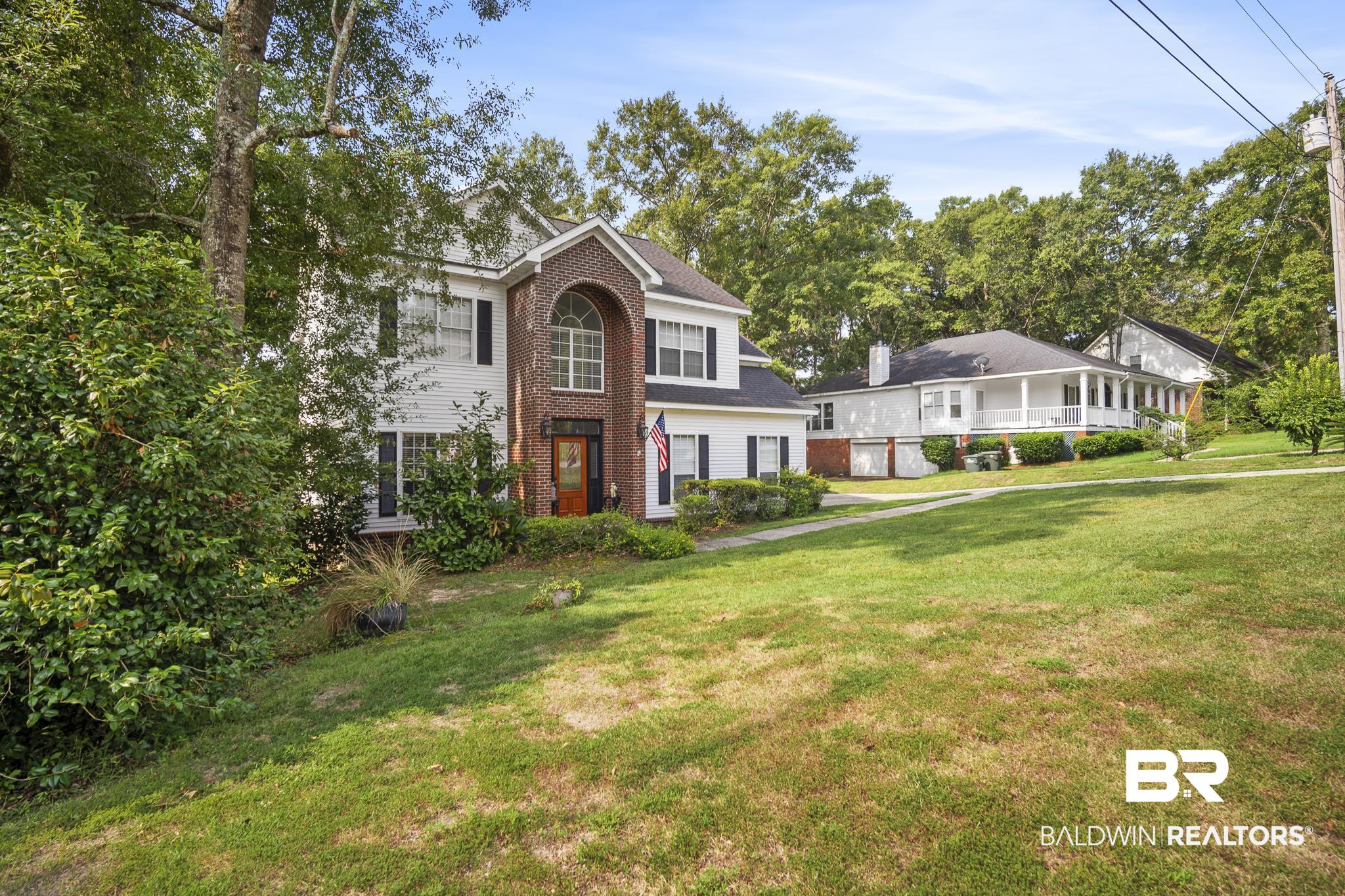 Two-story residence featuring a brick and white siding facade with dark shutters