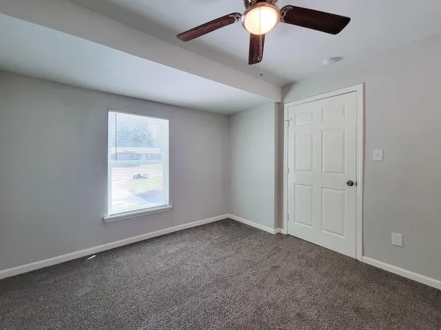 an empty room with a ceiling fan and window