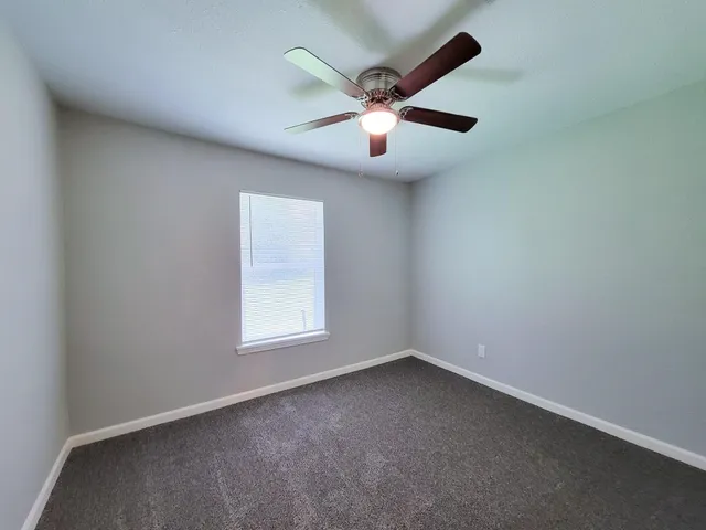 an empty room with a window and a fan