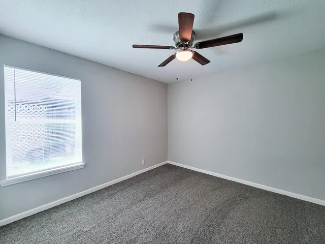 an empty room with windows and fan