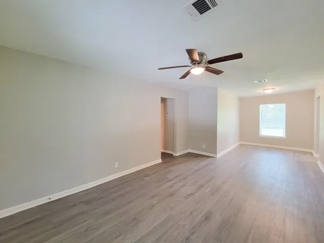 a view of an empty room with a window and wooden floor
