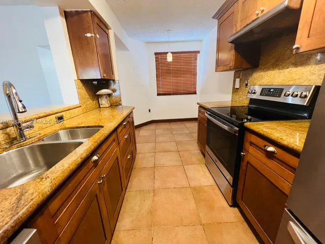 a kitchen with granite countertop a sink stove and cabinets