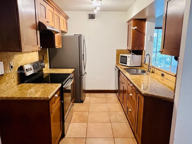 a kitchen with stainless steel appliances granite countertop a sink stove and refrigerator