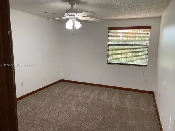 en empty room with windows and ceiling fan