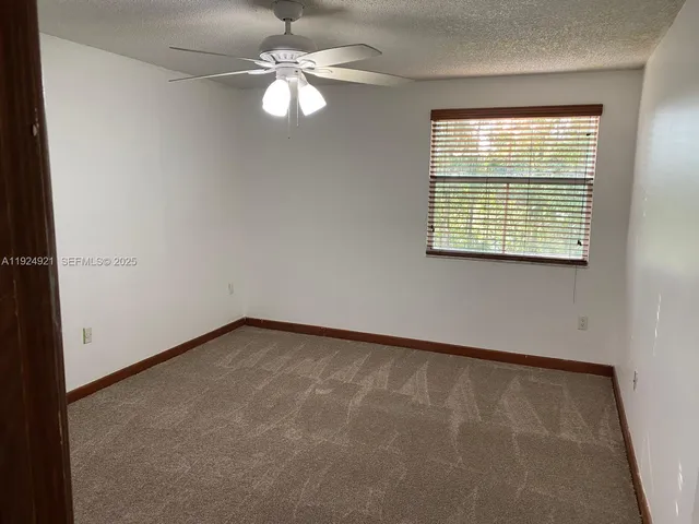 en empty room with windows and ceiling fan