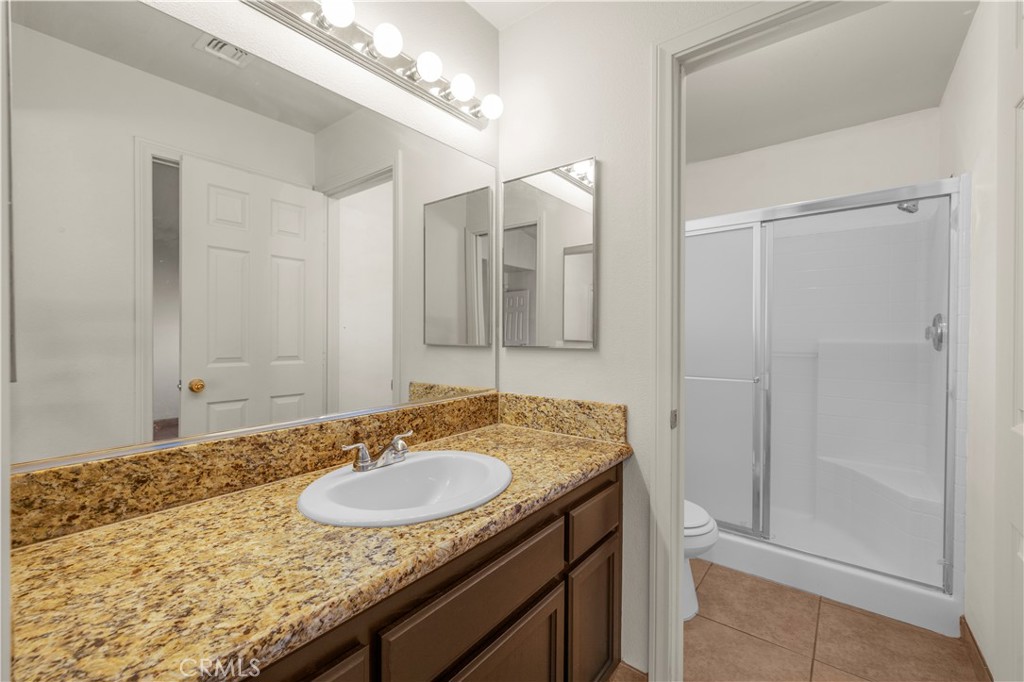57031 Selecta Avenue Yucca Valley, CA 92284 - Photo 29 of 56 a bathroom with a granite countertop sink a mirror and a shower
