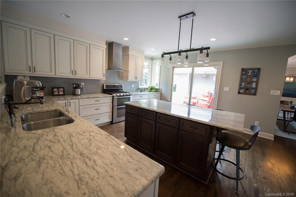 2837 Sharon Road Charlotte, NC 28211 - Photo 4 of 24 a kitchen with stainless steel appliances granite countertop a stove a sink a refrigerator white cabinets and wooden floor