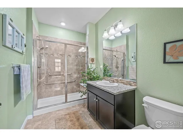 a bathroom with a granite countertop sink a toilet a large mirror and shower