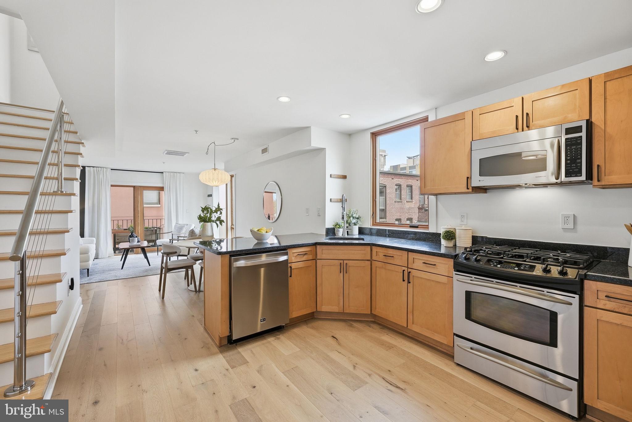 2713 Ontario Road Northwest, Unit 5 Washington, DC 20009 - Photo 4 of 35 a kitchen with stainless steel appliances kitchen island granite countertop a stove top oven a sink dishwasher a dining table and chairs with wooden floor