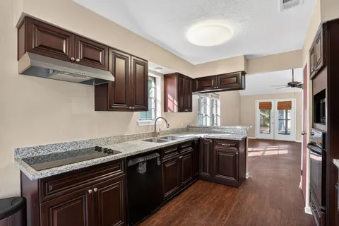 a kitchen with granite countertop a sink stove and cabinets