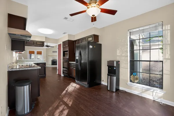 a view of an empty room with wooden floor and a ceiling fan