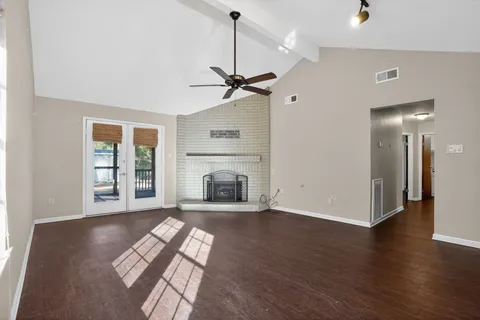 a view of a livingroom with a fireplace a ceiling fan and wooden floor
