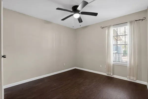 a view of an empty room with a window and wooden floor
