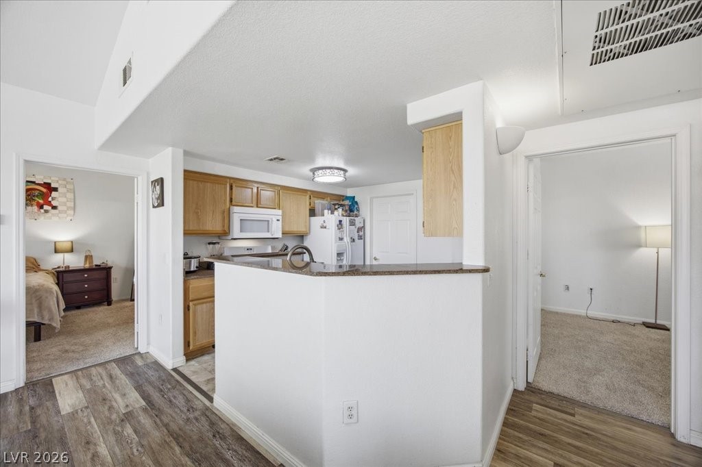 10550 West Alexander Road, Unit 2164 Las Vegas, NV 89129 - Photo 9 of 27 A compact kitchen with light wooden cabinetry offers modern appliances and convenient counter seating.