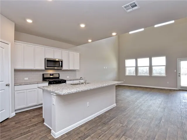 a kitchen with stainless steel appliances granite countertop a stove a sink and white cabinets