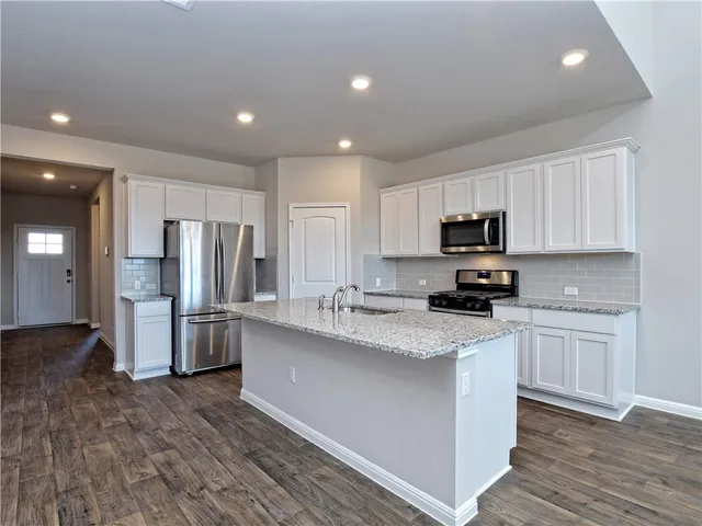 a kitchen with refrigerator a microwave and cabinets
