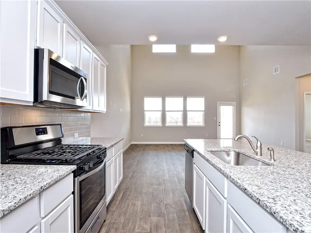 a kitchen with granite countertop a sink wooden floor and stainless steel appliances