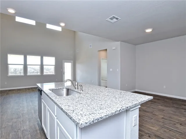 a kitchen island with granite countertop a sink and a wooden floor