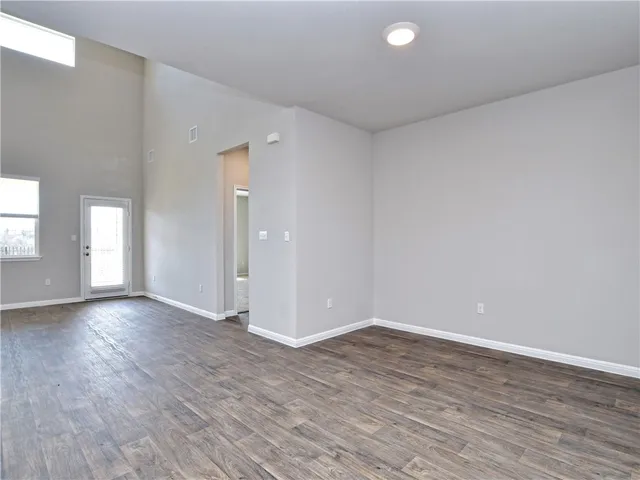 a view of an empty room with wooden floor and windows