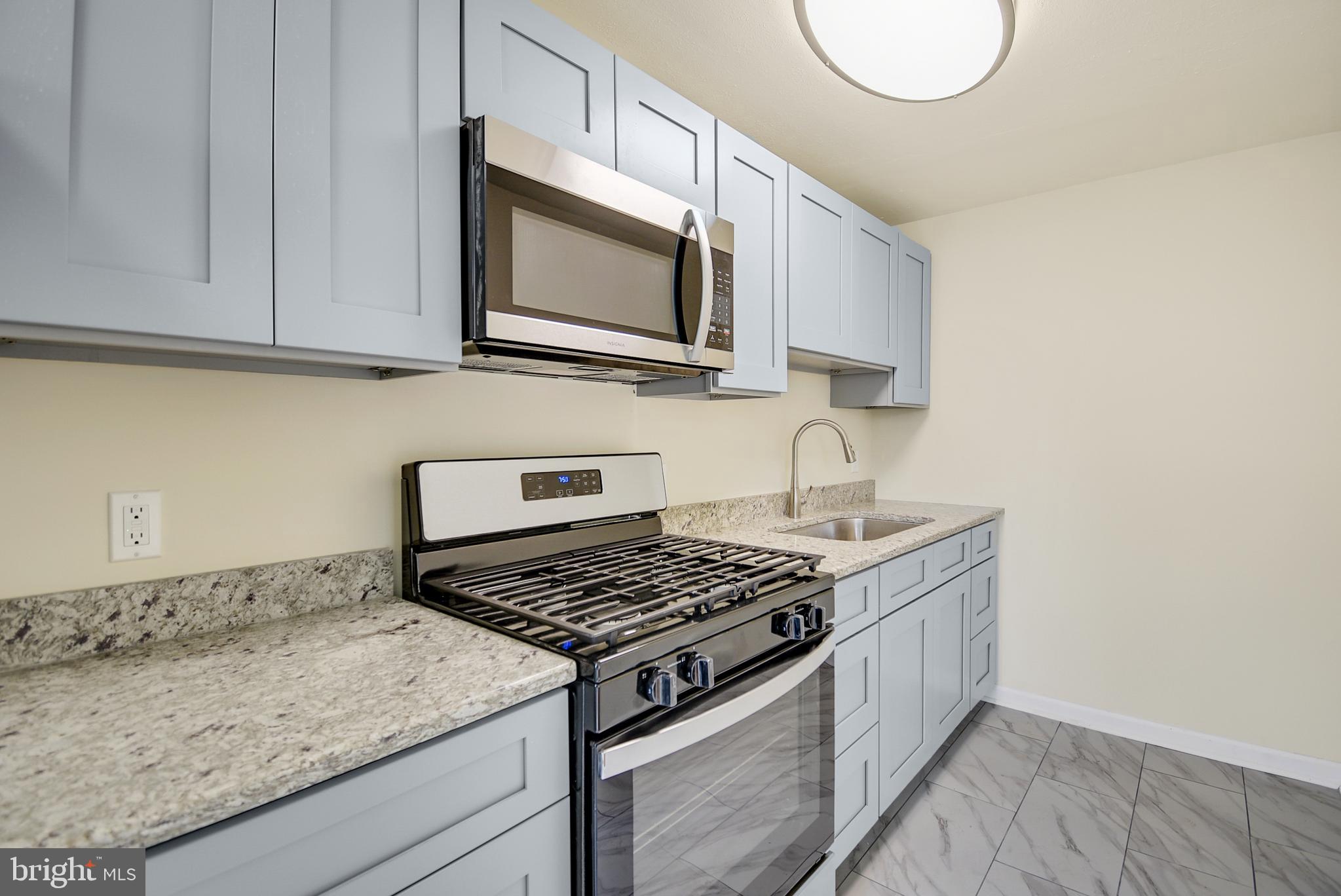 a kitchen with granite countertop a sink stove and microwave