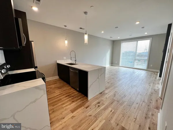 a large kitchen with stainless steel appliances kitchen island granite countertop a refrigerator and a sink with wooden floor