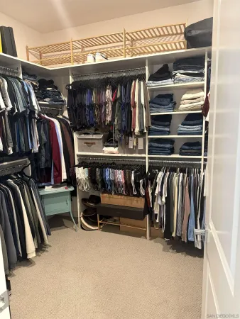 a view of walk in closet with clothes and shoes