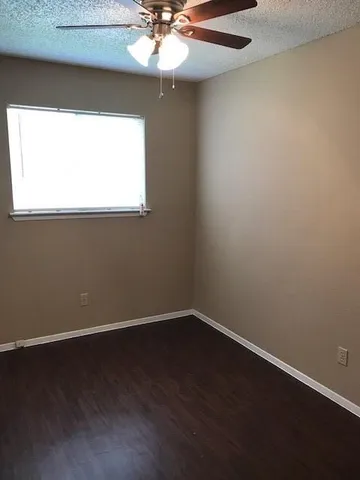 a view of a small space with wooden floor a chandelier fan and a window