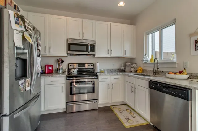 a kitchen with stainless steel appliances granite countertop a refrigerator and a stove top oven