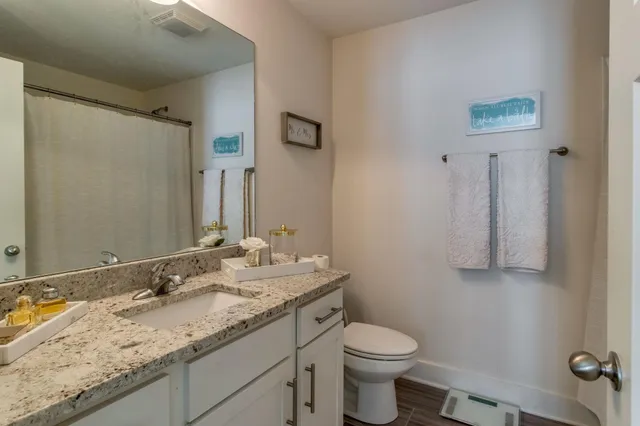 a bathroom with a granite countertop sink toilet and mirror