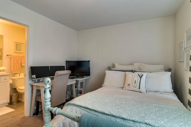 a bedroom with a bed and a flat tv screen on the dresser