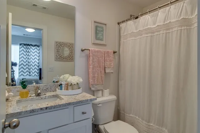 a bathroom with a granite countertop sink mirror vanity and toilet