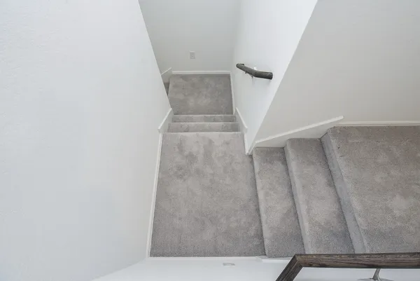 a view of a hallway with wooden floor and a bathroom